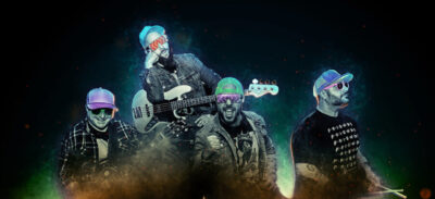 promo photo of 4 band members wearing baseball caps and sunglasses on dark background with neon light behind them