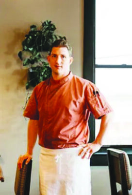 man wearing chef's uniform and apron in restaurant dining room