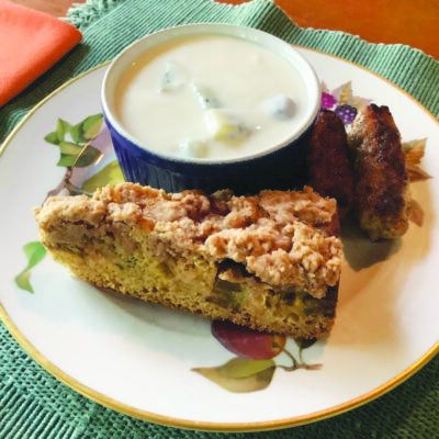 slice of rhubarb cake with crumb topping on plate with bowl of chowder