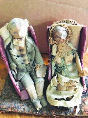 very old, tattered dolls dressed as a man and a woman, sitting on their little armchairs