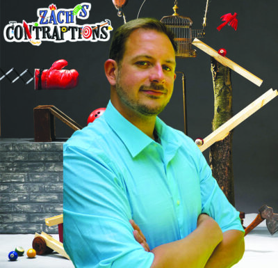 man with arms crossed, smiling slightly, in front of collage of diy mechanical contraptions