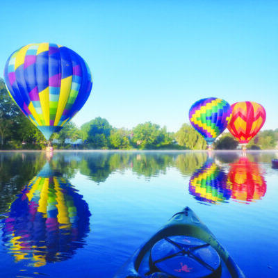 3 colorful hot air balloons landing on lake on sunny day