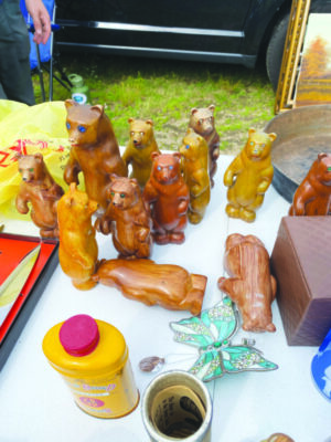outdoor table at flea market, with plastic figures shaped like standing bears, painted to look like wood
