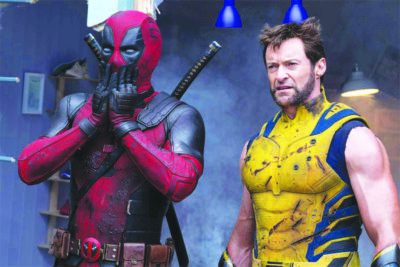 film still from Deadpool and Wolverine with actors as characters standing together reacting to something offscreen