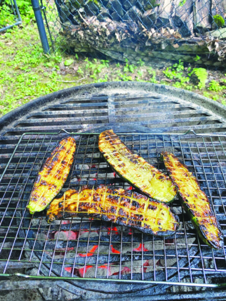 4 slices of zucchini cut lengthwise on grill, well cooked with grill lines in grid pattern