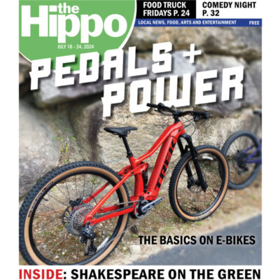 front cover of Hippo news, showing red e-bike leaning against stone wall, with title pedals plus power