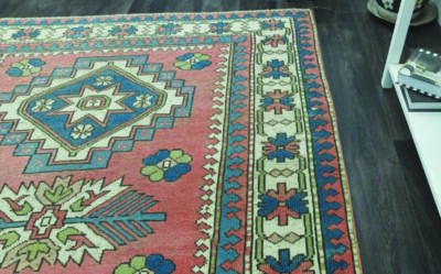 part of woven rug with geometric designs in muted reds and blues