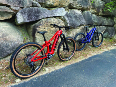 red and blue e-bikes leaning against stone wall on side of road