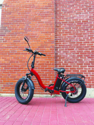 red e-bike on brick sidewalk beside brick wall