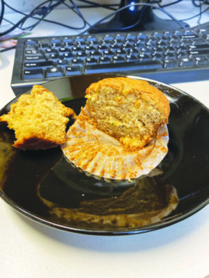 muffin cut in half sitting on plate in front of computer keyboard