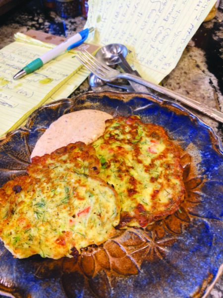 2 zucchini pancakes on plate with sauce on side