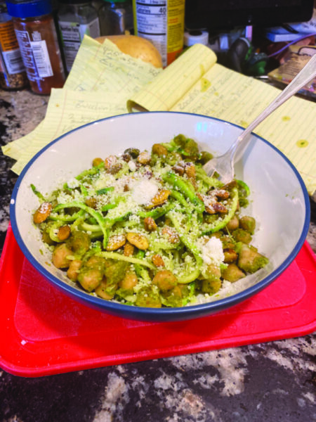 bowl with green noodles and chickpeas covered in parmesan cheese