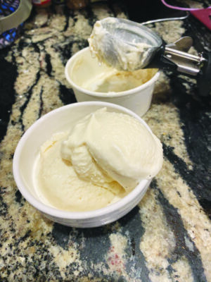 two styrofoam cups with scoops of light colored ice cream sitting on marble counter