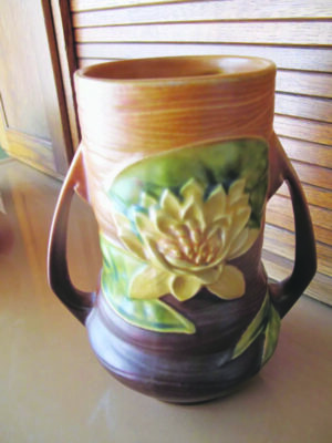 ceramic mug with handle on each side, decorated with carving of water lily