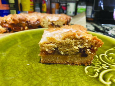 square of pastry with dough bottom, layer of rhubarb jam and crumbly topping on plate, layers visible from the side