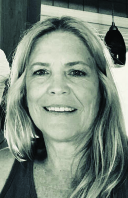 black and white headshot of long haired middle aged woman, smiling