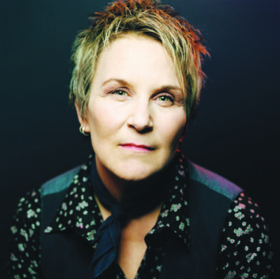 middle aged woman with short fashionable hair, looking serious, dark lighting, black background