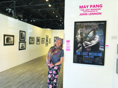 woman leaning against wall at art gallery, photographs lining walls behind her