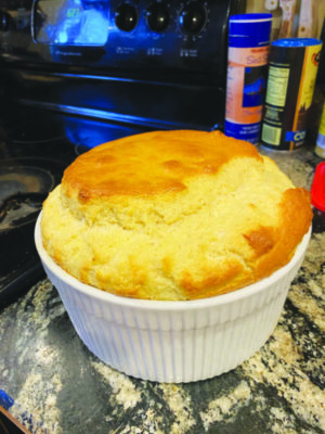 souffle with rounded top in white circular baking dish with tall sides, sitting on counter