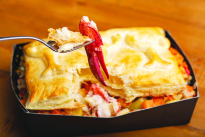 rectangular pie in cardboard container, flaky top crust, fork spearing piece of lobster out of it