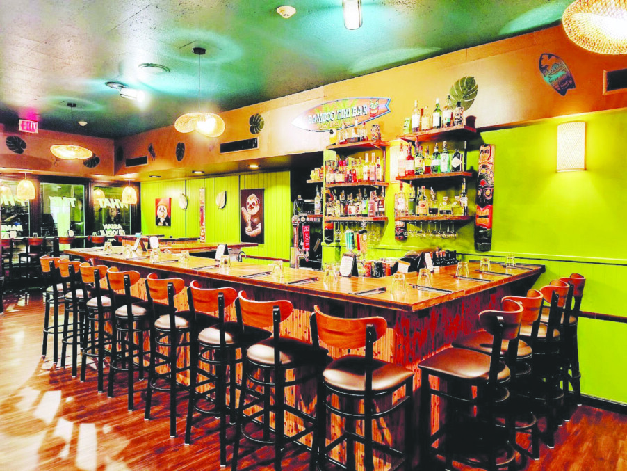 inside of restaurant with painted green walls, bar against wall with tall chairs lining it outside, fun colorful atmosphere