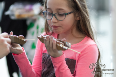 girl with glasses holding two chocolate samples