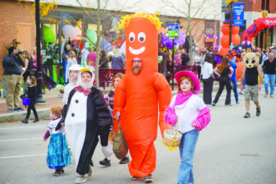 family dressed in costume walking down street in halloween parade