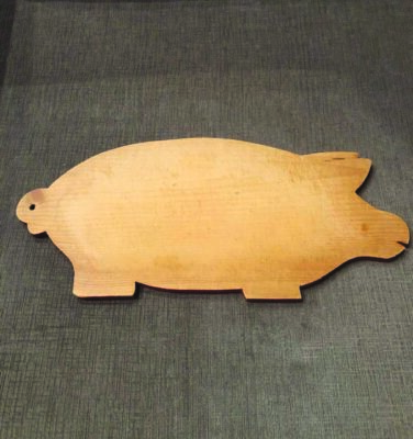 wooden board cut in the shape of a fat pig with short legs and short snout