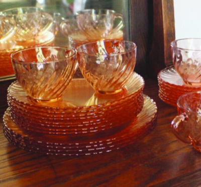 stack of glass plates with two small cups sitting on top, glass tinted pink