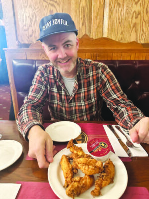 man sitting in booth at restaurant with plate of chicken tenders in front of him