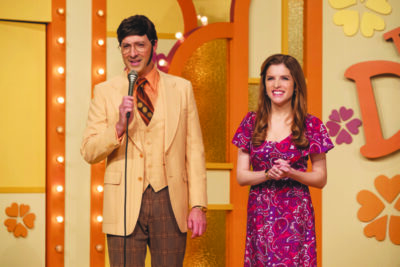 scene from movie Women of the Hour showing game show host standing with female contestant, seventies style orange background