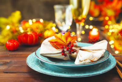 Thanksgiving autumn place setting with cutlery and arrangement of colorful fall leaves.