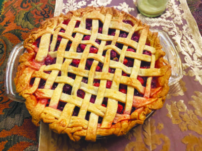 cranberry pie with lattice top on embroidered table cloth, seen from above