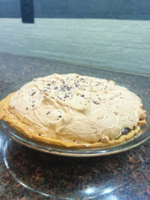 pie with mound of cream on top, topped with chocolate flakes, sitting on counter