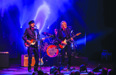 three men on stage during rock concert