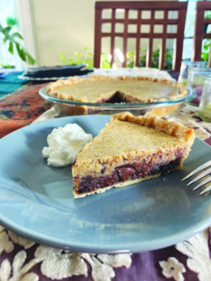 triangular piece of pie sitting on plate beside dollop of whipped cream, pie pan in background