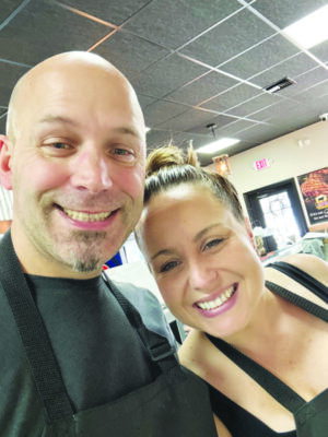 A butcher and his wife pose and smile for a selfi