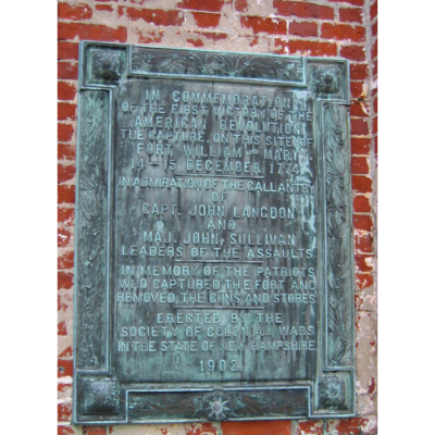 weathered metal plaque with raised text, attached to brick wall