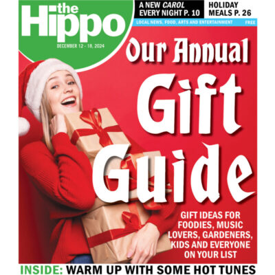 front of the Hippo magazine, showing woman wearing santa hat carrying stack of wrapped gifts