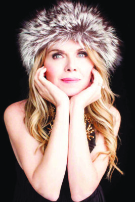 headshot of woman wearing furry hat, chin resting on her hands