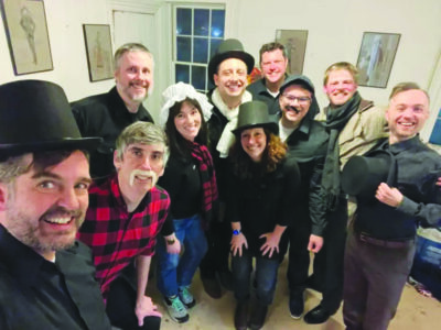 group of actors in small room, posing for photo, half in costume