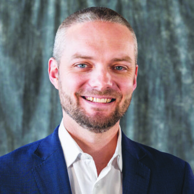 headshot of man with very short hair and short beard wearing collared shirt and blazer