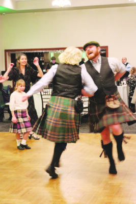 A man and woman dance and spin around in traditional Irish clothing