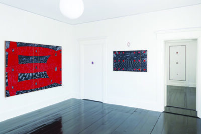 inside of gallery with multiple rooms, white painted walls, shiny black floor, large abstract paintings hung