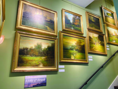 A series of landscape paintings along a staircase wall.