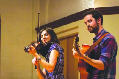 A husband and wife play a violin and guitar at a Contra dance