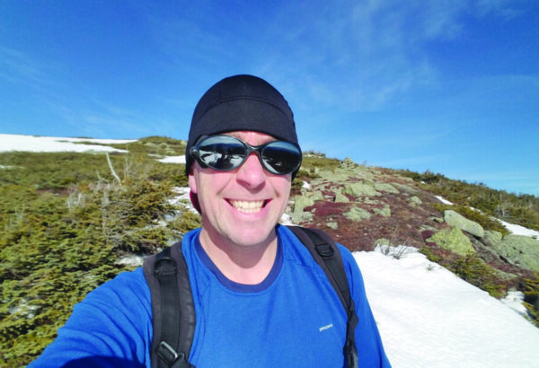 Man in sunglasses taking a selfie while hiking.