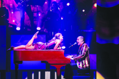 A woman lies on a piano as she and the pianist sing aa duet