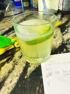 A cucumber flavored drink in a small glass sitting on a countertop