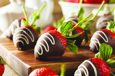 A pretty collection of chocolate-covered strawberries with white chocolate drizzle.